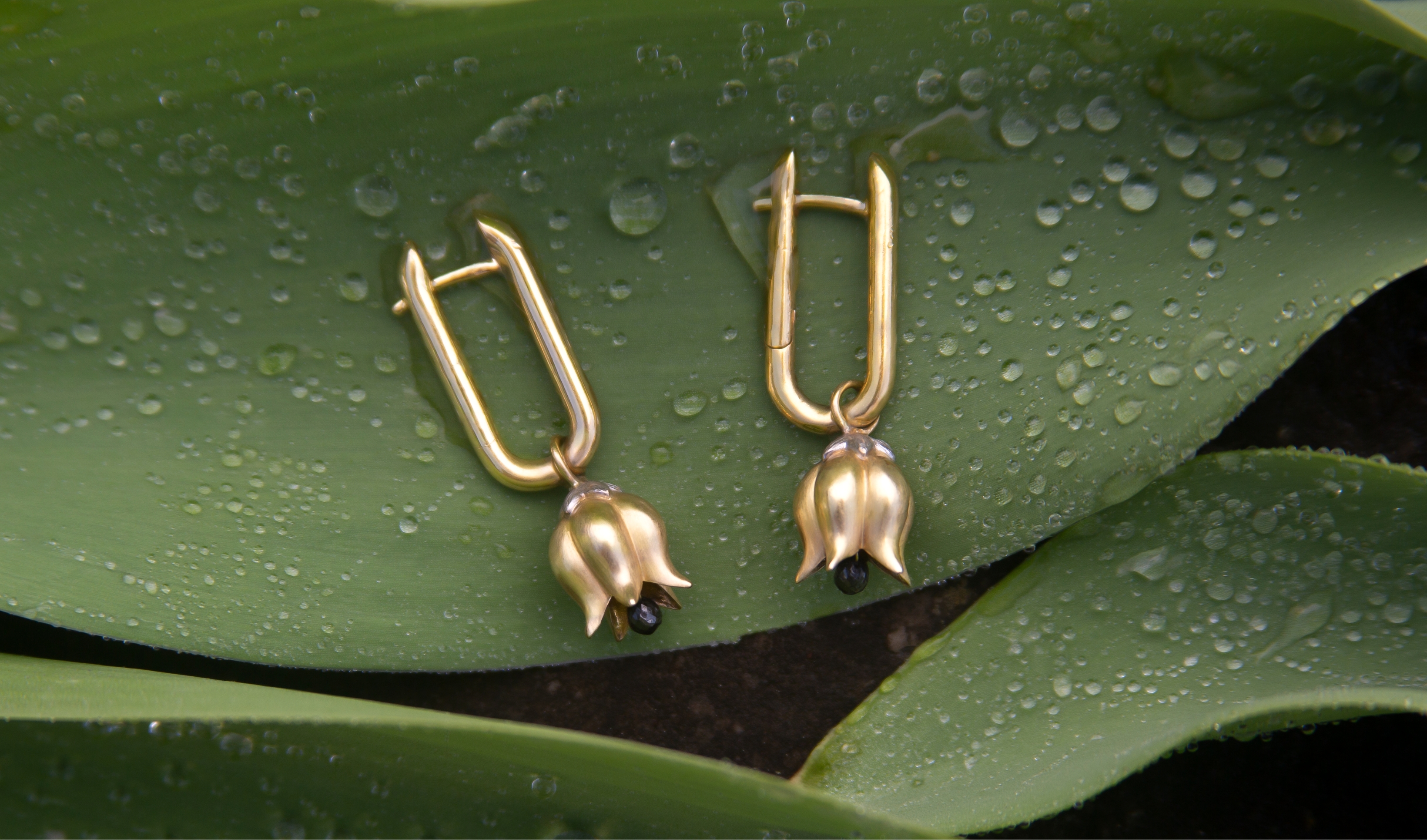 gold tulip earrings on a plant leaf