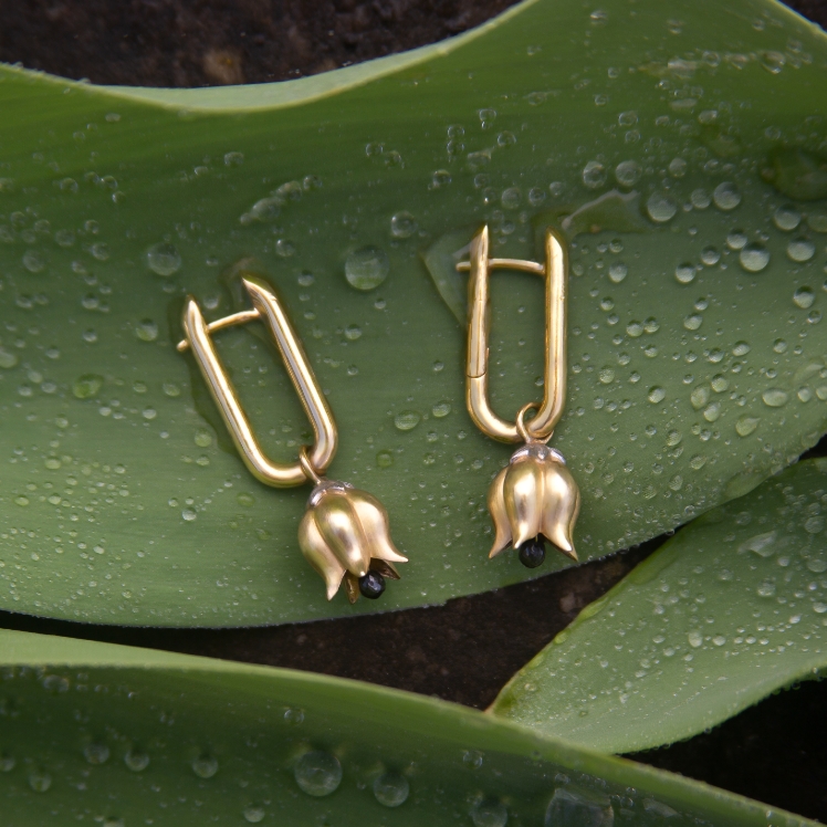 gold tulip earrings on a plant leaf